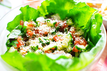 Vegetable salad with cherry tomatoes, cucumber, lettuce and sesame seeds in bowl. Healthy and proper nutrition. Selective focus.