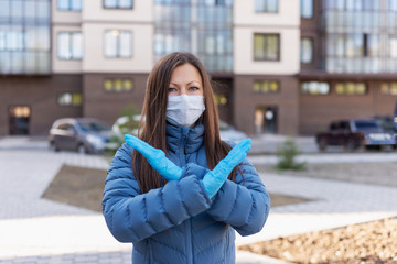 Covid concept 19. portrait of a Caucasian woman on the street and showing a stop gesture with her hand, the woman puts on a protective mask and gloves to prevent the rapid spread of the corona virus