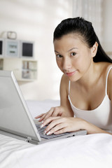 Fototapeta premium Woman lying forward on bed using laptop