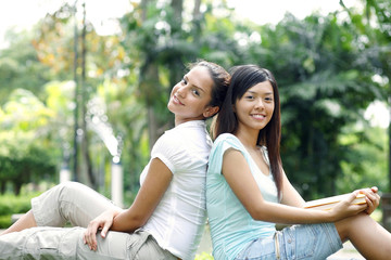 Women leaning back to back, looking at camera