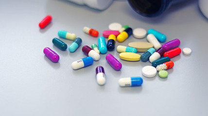 White and Brown glass medicine bottles with colorful tablets, pills, capsules drugs using for treatment and cure the disease or sickness. Drug prescription for medication isolate in white background.