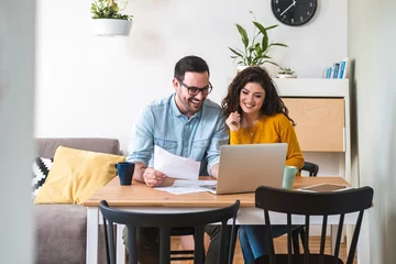 Fotobehang Happy husband and wife read good news online at laptop, smiling man holding documents receiving positive decision from bank © Tijana