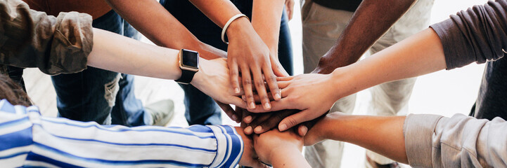 Group of diverse people stacking hands in the middle - Powered by Adobe