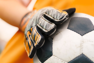 Soccer background detail image. Close up on football ball and sports goalie gloves. Footballer goalkeeper holding ball in hands