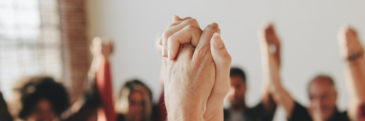 Group of diverse people holding hands up in the air