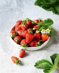 Fresh strawberries in a bowl on a gray background, still life