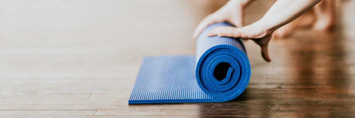 Yogi rolling her blue yoga mat