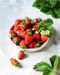Fresh strawberries in a bowl on a gray background, still life