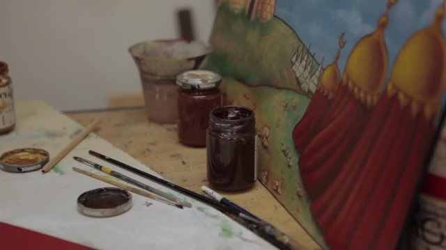 Close-up of set designer hand dipping a paint brush.