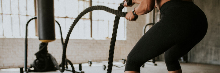 Sportive woman doing a battle rope in a gym
