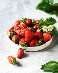 Fresh strawberries in a bowl on a gray background, still life