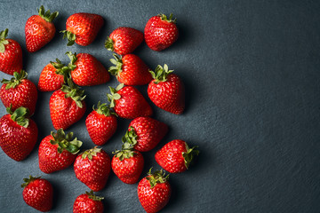 Top view of some red strawberries on a dark background.