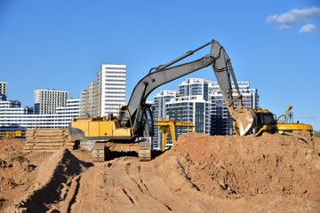 Excavator working at construction site on road work. Backhoe digs ground for the foundation and for...