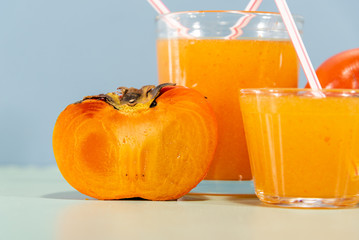 Fresh fruit juice and persimmon (Diospyros kaki L.) on blue background