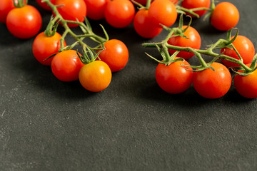 close up of fresh ripe cherry tomatoes on black background with copy space. Ingredient for mediterranean cuisine.