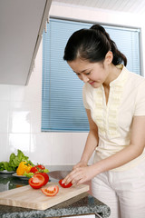 Woman cutting tomato in the kitchen