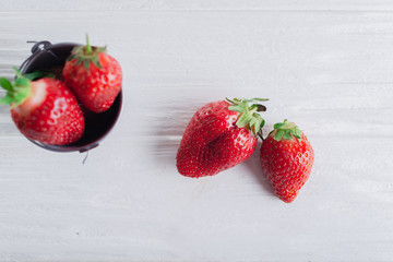 Juicy fresh Strawberries in a small iron bucket on a white wooden background