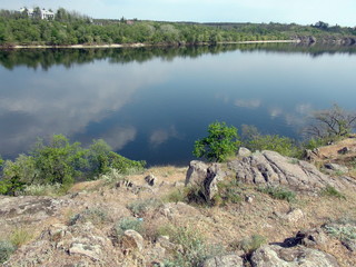 Landscape of the rocky shore covered with spring vegetation against the background of the Dnieper water mirror surrounding the island of Khortytsia.