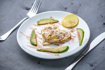 Healthy romantic Breakfast of fried eggs in the shape of a heart with slices of avocado on a white plate.