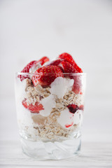 Strawberry dessert in a plate with ice cream and cream on a white wooden background