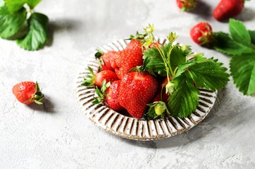 Fresh strawberries in a bowl on a gray background, still life