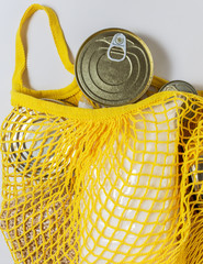 A set of long-term storage products in a string bag on a white background. Food donations