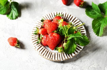 Fresh strawberries in a bowl on a gray background, still life