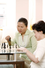 Women playing chess game at home