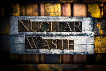Photo of real authentic typeset letters forming Nuclear Waste text with on vintage textured silver...