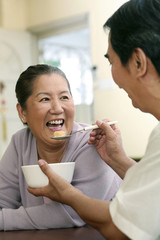 Senior man feeding senior woman cereal