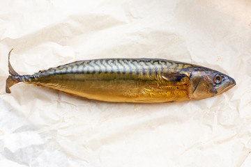 smoked mackerel fish lies on light paper, a delicious fatty snack