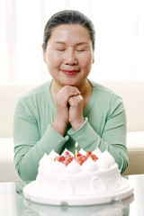 Woman making a wish in front of birthday cake