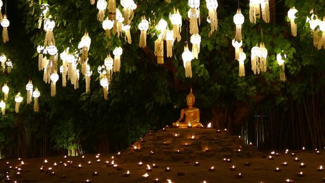 golden buddha image statue with candle light and paper lantern
