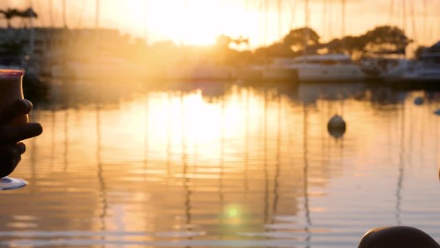 Two girls enjoying life toasting drinks making cheers in the port with boats during sunset slow Motion 