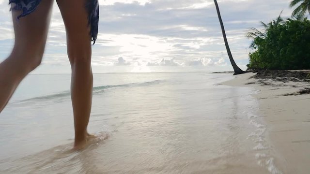 Feet of a young girl walking barefoot on the sandy beach during the day in Guadeloupe