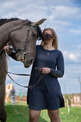 A girl next to a horse on a farm in the background of a sky.