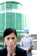 Businesswoman covering her nose, colleague in safety helmet and protection mask watching