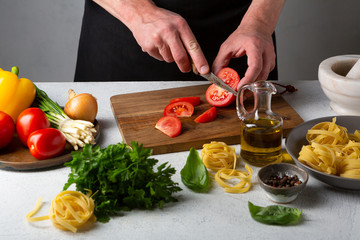 Preparing pasta men hands slicing tomato