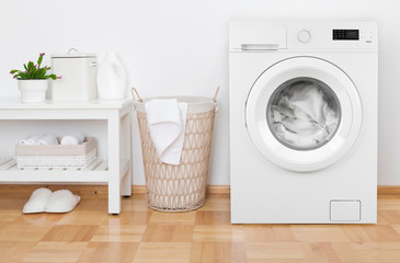 Laundry room interior with washing machine, basket and white shelves