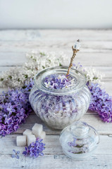 Obraz na płótnie Canvas Lilac flowers and sugar in a glass jar