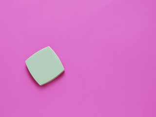 green compact powder on a pink background