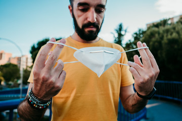 .Young man starting to go outside after quarantine caused by the covid virus 19. Putting on the mask correctly to protect himself from the virus. New normal. Social distancing.