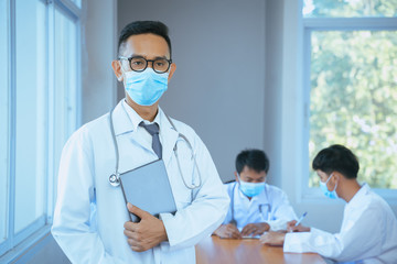 Doctors wearing protective mask to Protect Against Covid-19 use tablets with digital of technology working in clinic or hospital.