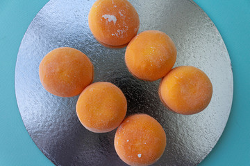 Mochi with mango. Premium ice-cream wrapped in sweet rice dough, traditional japonese desert. Gluten Free. Orange on pastel blue