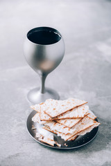 Communion still life. Unleavened bread, chalice of wine, silver kiddush wine cup on grey...