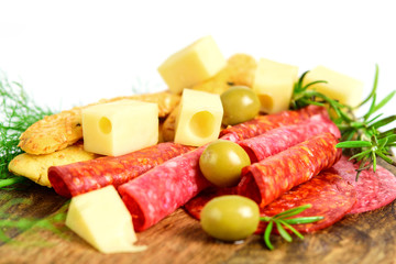 Slices of chorizo, salami, cheese, olives, bread sticks and green herbs on the cutting board closeup, white background. Healthy mediterranean food for snack.