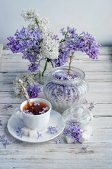 a Cup of tea and lilac with sugar on a wooden table
