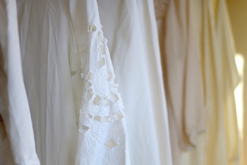 Fototapeta na wymiar White vintage blouses on a clothing rack. Selective focus.