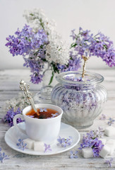 Obraz na płótnie Canvas a Cup of tea and lilac with sugar on a wooden table