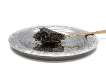 black caviar on a beautiful silver plate on a golden tea spoon